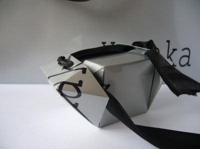 Boite faite en découpant un carré dans un sac "Xanaka". Le ruban qui sert de fermeture pour cette boite en papier servait de poignée au sac d'origine. 
