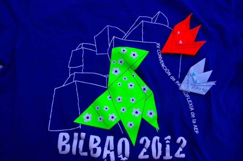 Deux badges sur un tee shirt de la convention AEP 2012
Le badge orange est plié dans du kami de 15x15 cm, le blanc dans du kami de 10x10 cm
